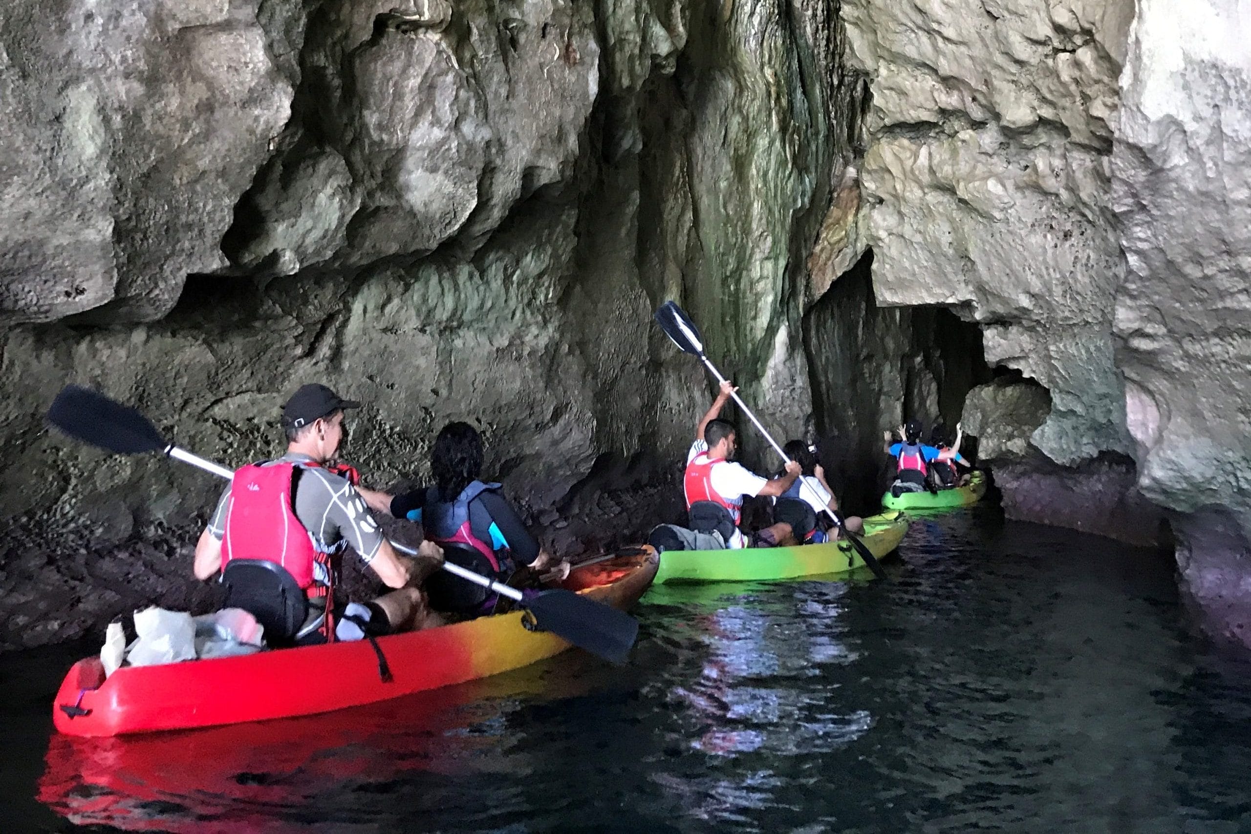 Un grupo de kayaks dentro de una cueva en Cala en Porter, sur de Menorca. Excursión guiada por Menorca en Kayak