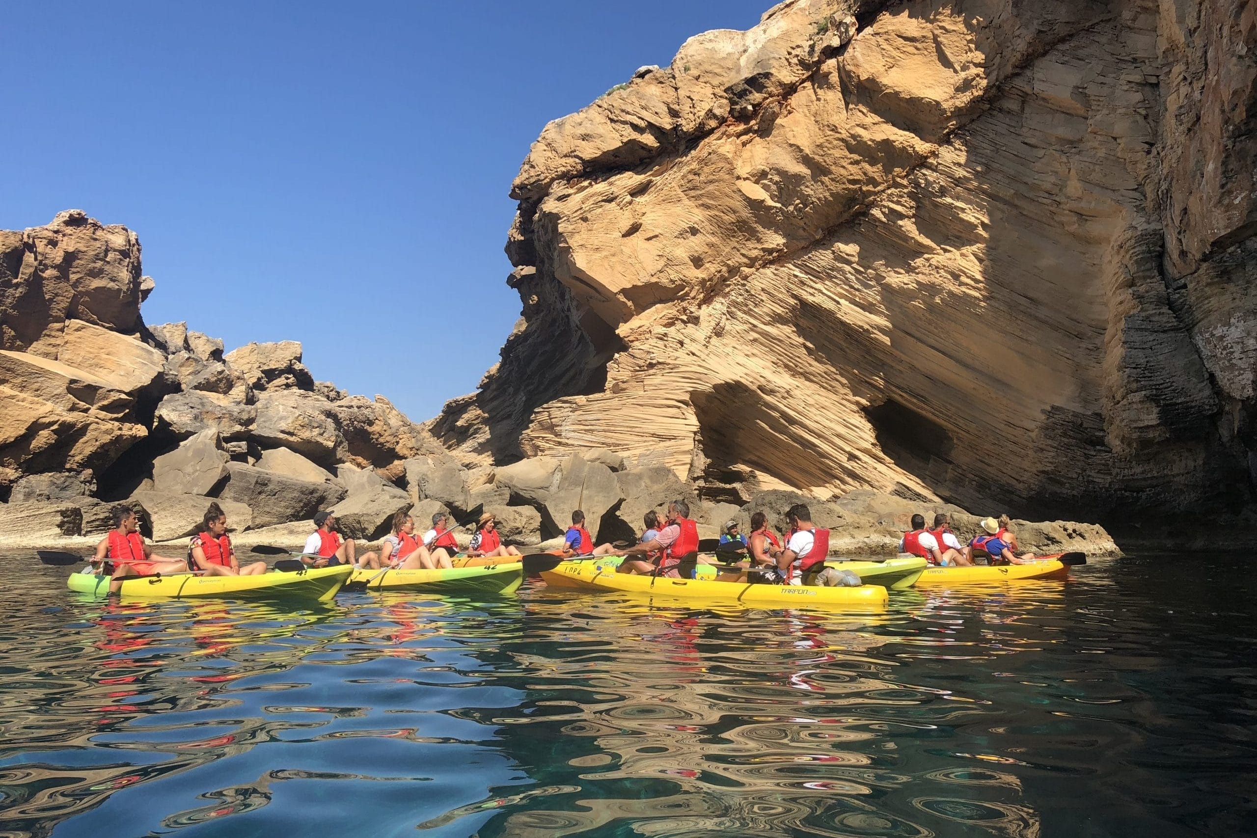 Grupo de amigos en kayak en la zona de las cuevas en el sur. Acantilados y dunas fósiles. Cerca de la cueva d'En Xoroi en Cala en Porter. Menorca