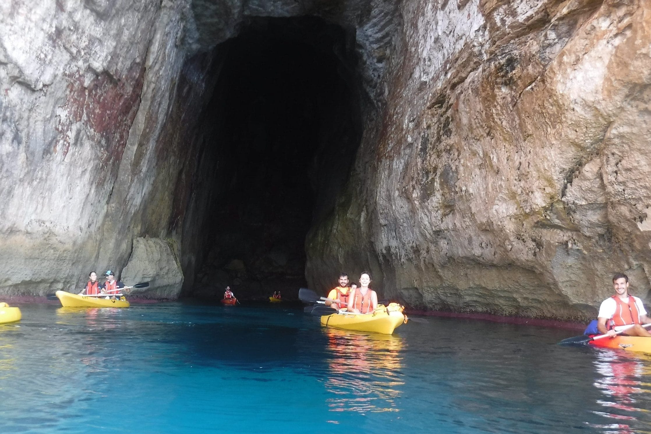 Grupo de kayaks dentro de una cueva en la zona del sur, en Cala en Porter. Excursión guiada por Menorca en Kayak