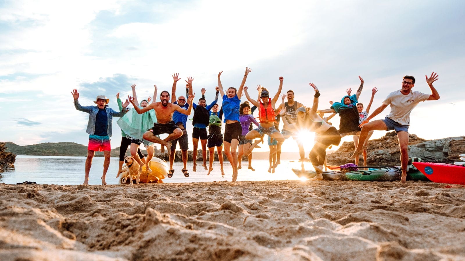 Grupo de amigos saltando en la playa después de una actividad en kayak en la Isla de Colom en Es Grau.